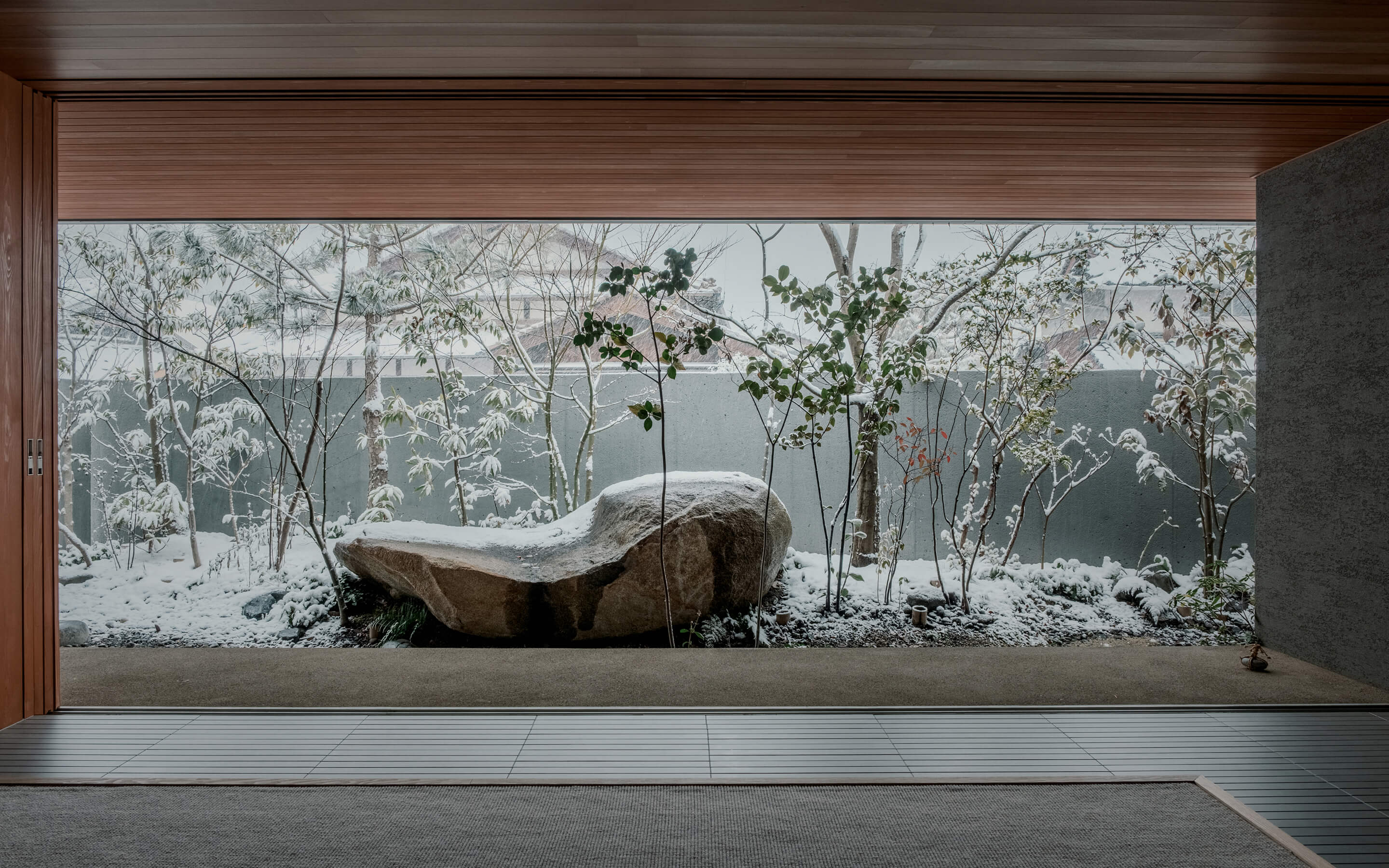 大きな窓から雪景色の庭園を眺める共用スペース。モダンな設計で開放的な空間。